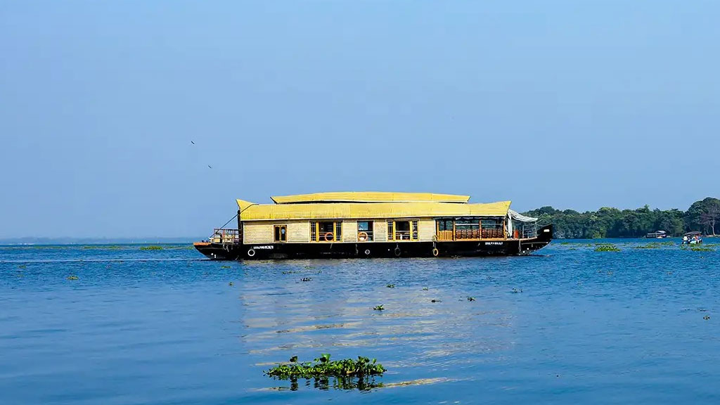 A serene view of a houseboat gliding across Vembanad Lake.